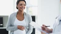 Pregnant woman speaks with a doctor, who is taking notes